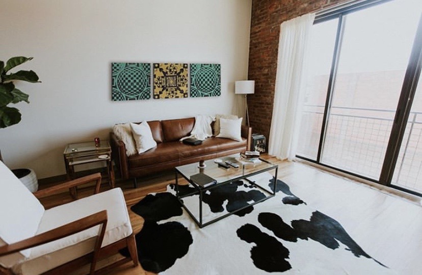 Un salon avec fauteuil et canapé et un triptyque de dalles sur le mur